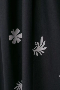 Gros plan du tissu d'une robe midi noire avec des motifs floraux et de feuilles gris clair