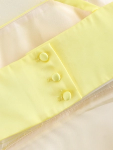 Detailed view of three fabric-covered buttons on a light yellow sleeveless summer dress
