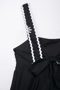 Détail de robe midi imprimée avec bretelles en dentelle marguerite et grand nœud noir au dos