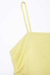 Detailed macro view of thin spaghetti straps and light yellow textured fabric of the midi dress