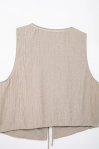 Detail of light beige textured vest showing cotton-linen fabric and tie-back strings