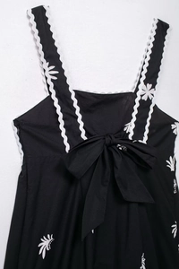 Détail d'une robe midi fleurie avec nœud au dos et bretelles ondulées à croquet blanc