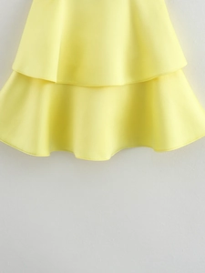 Detail of light yellow summer dress showing double-layered ruffled hem and smooth fabric