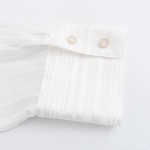 Detail shot of white shirt cuff with silver metallic stripes and pearl buttons