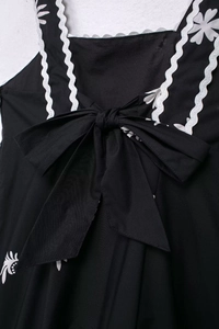 Détail d'une robe midi fleurie avec bretelles festonnées et un grand nœud central