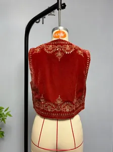 Close-up of golden floral embroidery and sequins on a red velvet waistcoat top