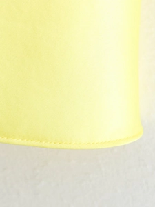 Close-up of the curved hem on a yellow satin summer dress with smooth silk texture