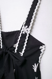 Détail de la robe noire fleurie avec dentelle festonnée blanche et nœud papillon au dos