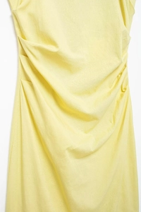 Detail of light yellow ruched fabric showing the textured knit pattern and elegant draping