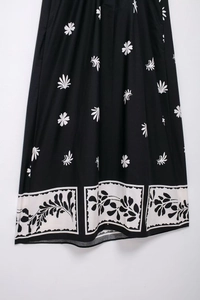 Détail d'une robe midi noire avec imprimé marguerites et bordure de style ethnique