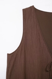 Detail of dark brown crinkle fabric on sleeveless V-neck top with drawstring design