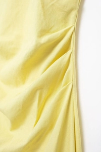Detail of ruched yellow cotton linen fabric showing fine stitching and natural texture