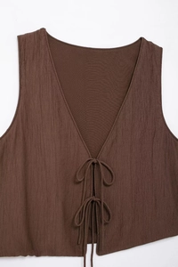 Detail of brown V-neck textured vest with front double ties and vertical pleats