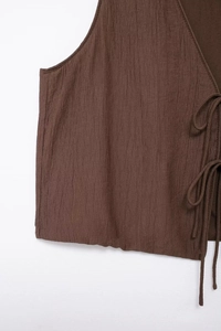 Detail of dark brown textured sleeveless top featuring delicate side tie-up strings