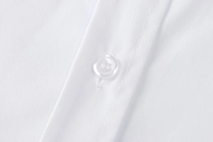 Close-up of white shirt detail featuring a resin button and premium twill fabric texture