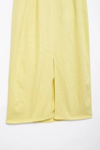 Detail view of the side slit and vertical texture on a light yellow midi dress fabric