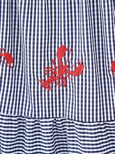 Close-up of blue gingham dress with red lobster embroidery and ruffled hem details