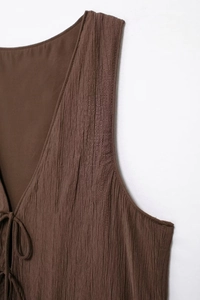 Close-up of deep brown textured fabric with pleated design and chic V-neck tie detail