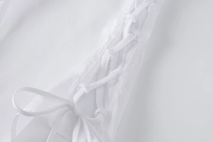 Detailed macro view of white shirt side lace-up design with neat stitching on plain fabric