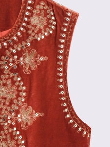 Detailed embroidery on red velvet vest with golden stitching and silver sequins