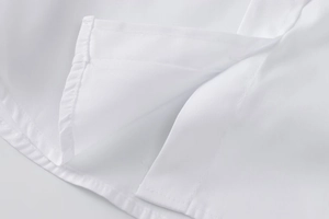 Detail view showing neat stitching and side slit on this white long sleeve shirt