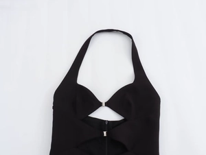 Detail of black halter dress featuring cutout design with silver metal buckles and zipper