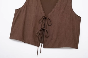 Detailed close-up of dark brown textured fabric and bow-tie closures on sleeveless top