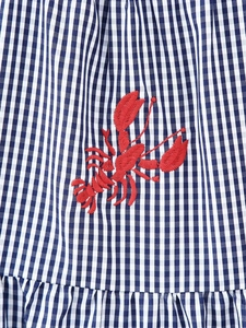 Close-up of blue gingham fabric with detailed red lobster embroidery and ruffled hem
