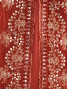 Detailed close-up of velvet vest featuring floral embroidery and silver sequins on brick red