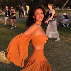 Close-up of orange pleated two-piece resort set featuring off-shoulder top and maxi skirt