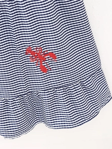 Close-up of blue gingham fabric with exquisite red lobster embroidery and ruffled hem
