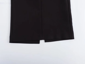 Detailed close-up of the back vent and neat stitching on a black halter neck dress hem