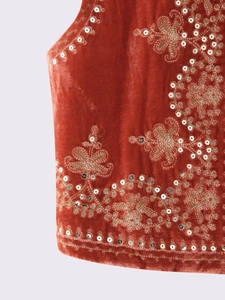 Close-up of rust velvet vest featuring golden embroidery and shimmering sequins detail