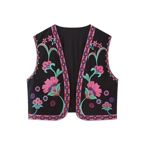 Gros plan de broderies ethniques aux motifs floraux colorés sur un gilet noir bohème