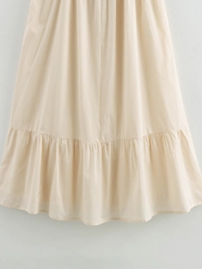 Detail of a beige midi dress featuring a structured ruffle hem and smooth fabric texture