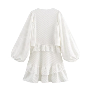 Detail of white puff sleeve dress featuring textured jacquard fabric and ruffled hemline