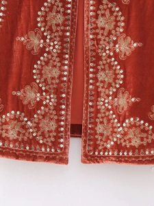 Close-up of velvet vest featuring golden floral embroidery and silver sequins detailing