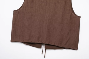 Detail view of brown textured sleeveless top featuring pleated fabric and drawstring hem