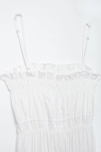 Close-up of white ruffled camisole with adjustable straps and pleats detail
