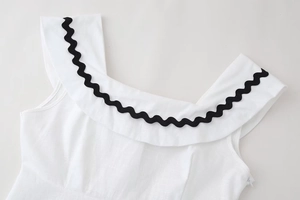Detail of white cotton linen dress showing ruffled collar with black rick-rack trim