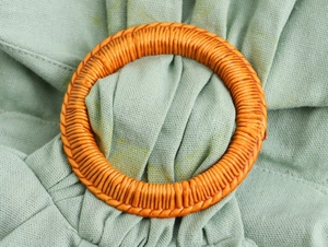 Detailed macro view of an orange woven buckle on green linen pleated dress fabric