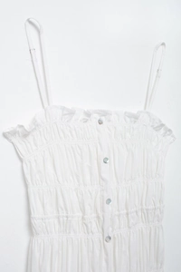Detailed view of white smocked camisole with delicate ruffles and pearl buttons