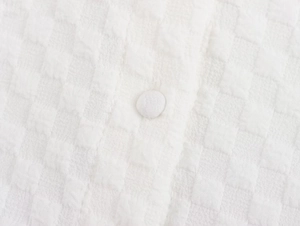 Detailed close-up of white seersucker fabric featuring a matching fabric-covered button