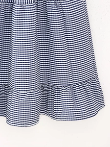 Detailed view of blue and white gingham dress fabric featuring a ruffle hemline finish