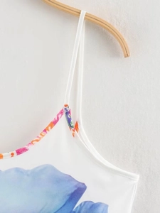 Detail of white summer dress with blue floral print and colorful braided straps