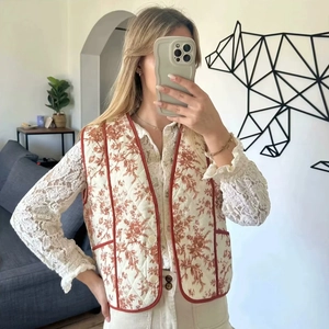 Close-up of vintage floral quilted vest with contrast red piping and round buttons