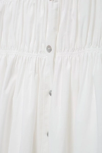 Detail of white summer dress showing ruched waist design and pearl luster buttons