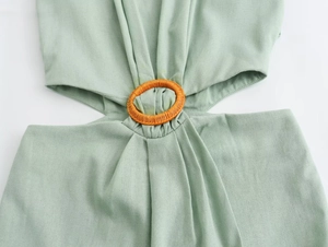 Detailed close-up of light green dress featuring a cutout waist and orange rattan ring buckle