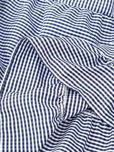 Macro shot of blue and white gingham fabric with layered ruffles and overlock stitching