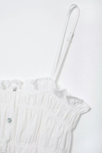 Detail view of white camisole with delicate ruffle neckline and mother of pearl buttons